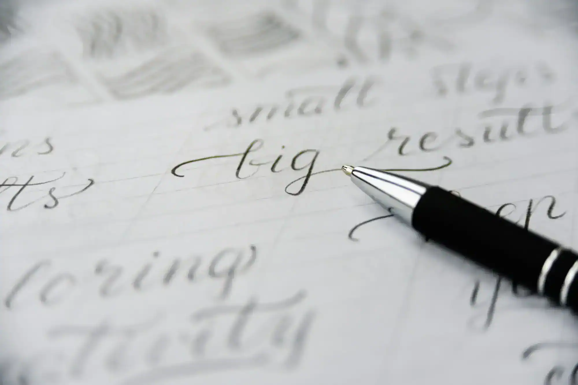 Close-up of a pen on paper with handwritten words, with the word “big” in focus.