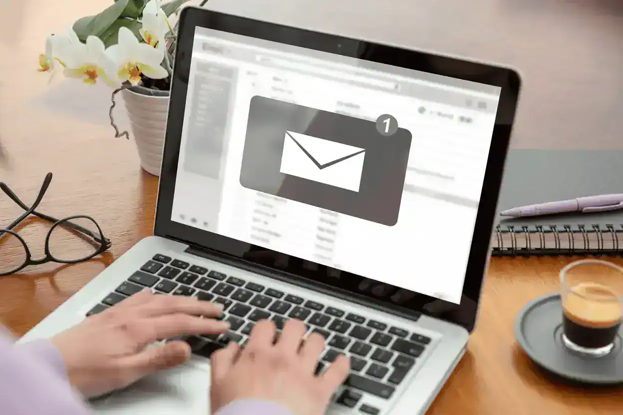 A laptop showing an email interface with an envelope in the center.