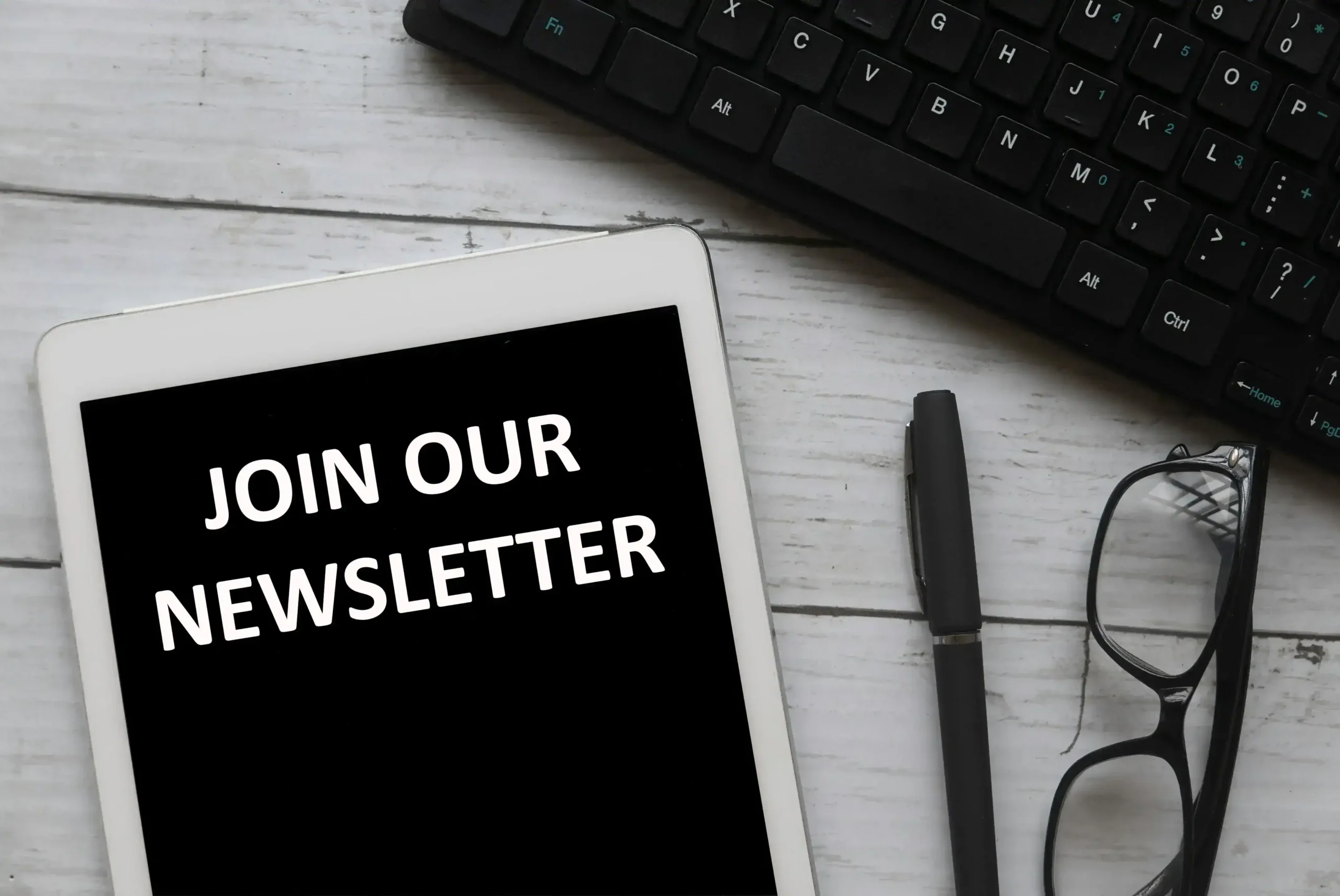 A tablet next to a keyboard writing: “Join our newsletter”