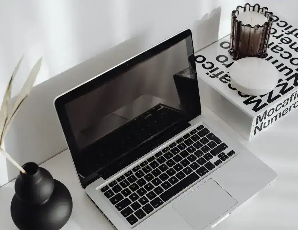 An elegant desktop with a laptop and black and white decorative items.