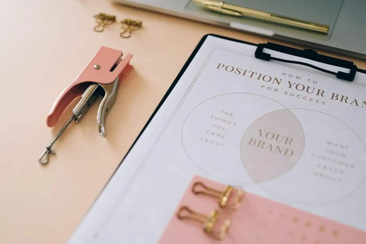 Pink stapler and branding document on a desk in a stylish office setup.